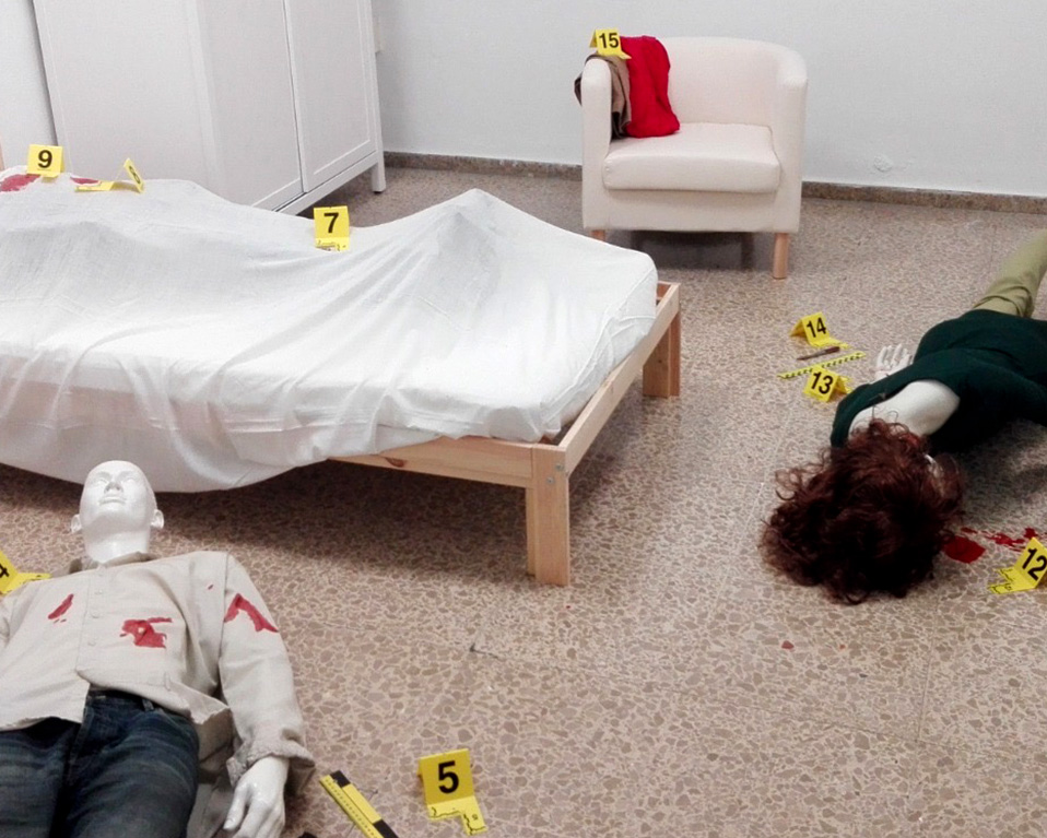Simulación de la escena de un crimen en una habitación realizada con muñecos de plástico.